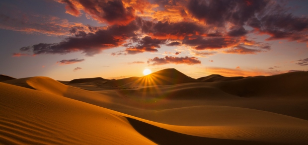 sun rising over sand dunes